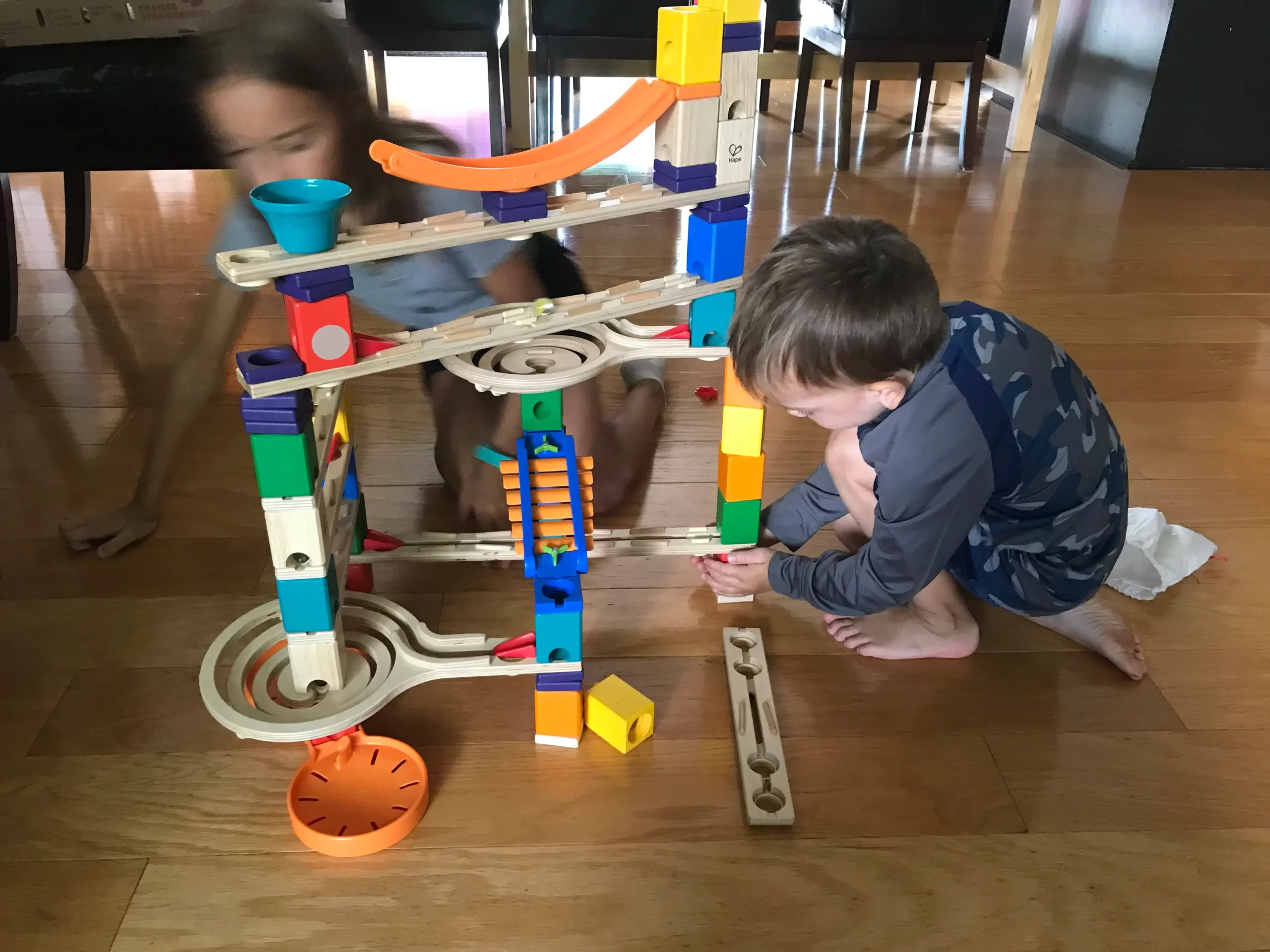 3 enfants qui apprennent les concepts de la programmation en jouant avec des blocs de bois pour concevoir un parcours de bille