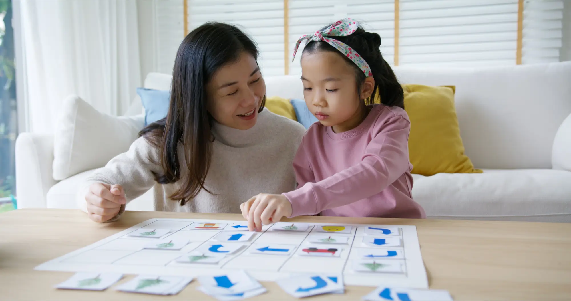 Maman et jeune fille 3 ans qui jouent avec de cartes de codage représentant des flèches de tous les côtés